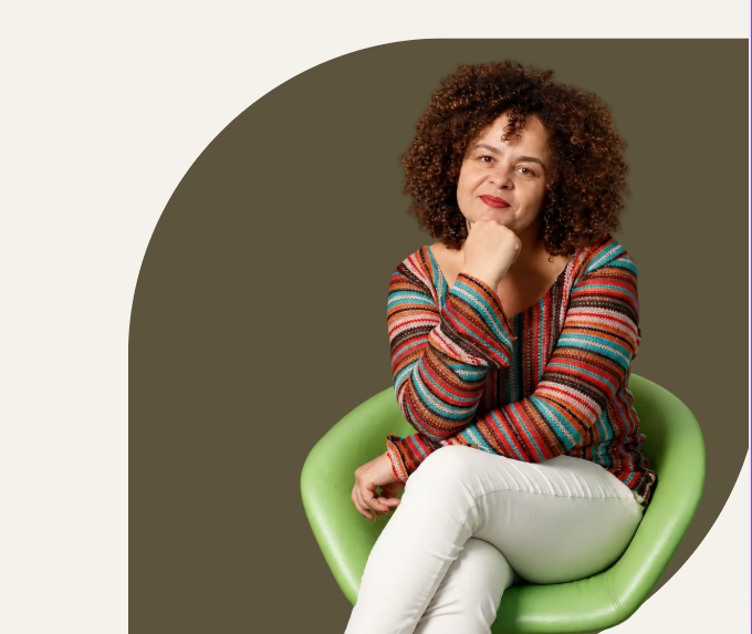 Sálvia Santana sentada em uma cadeira verde, com expressão acolhedora