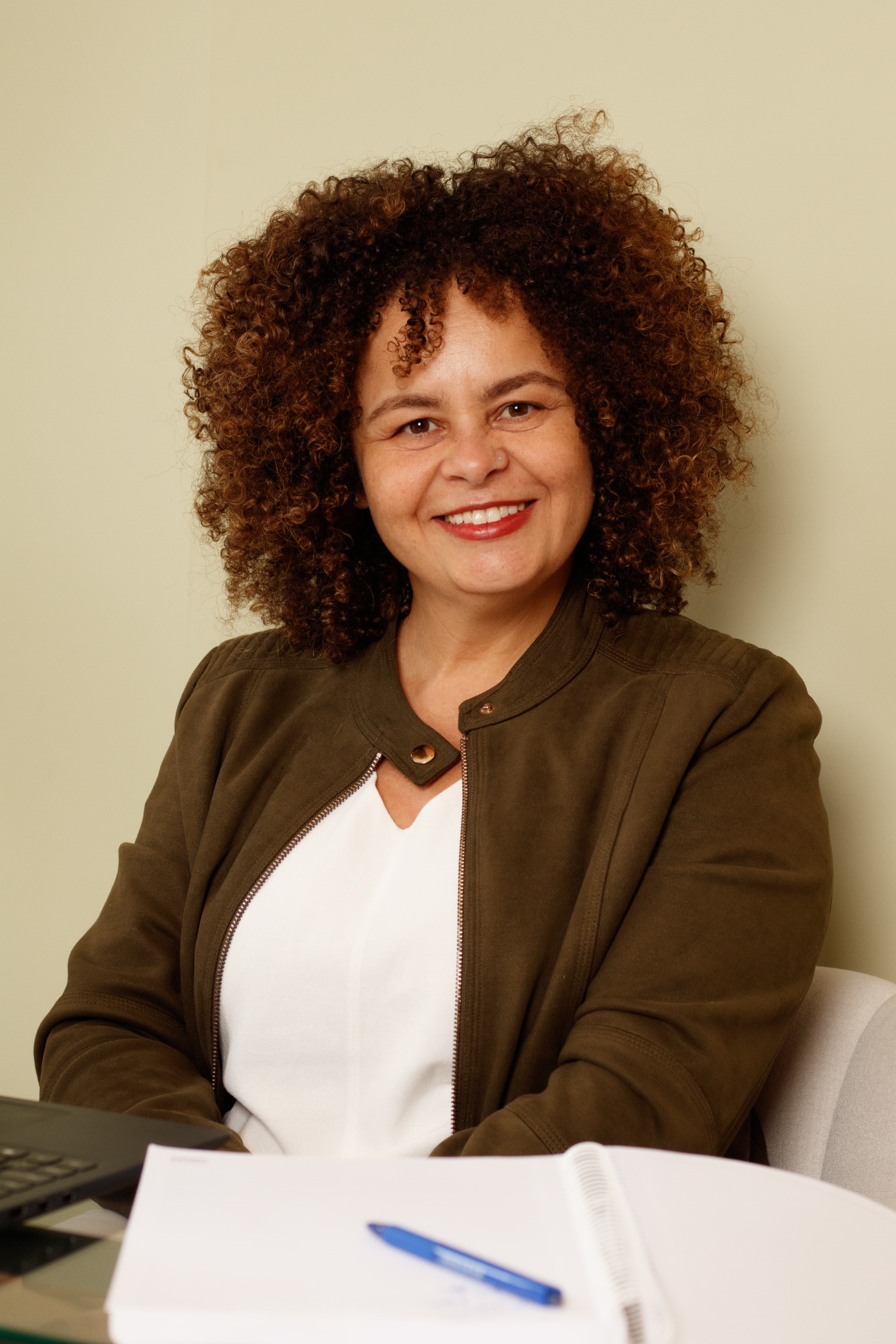 Sálvia Santana sorrindo, sentada à mesa com um caderno aberto